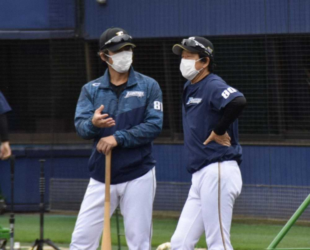 練習中にマスク姿で小笠原ヘッドコーチ兼打撃コーチ（左）と話し合う日本ハム・栗山監督