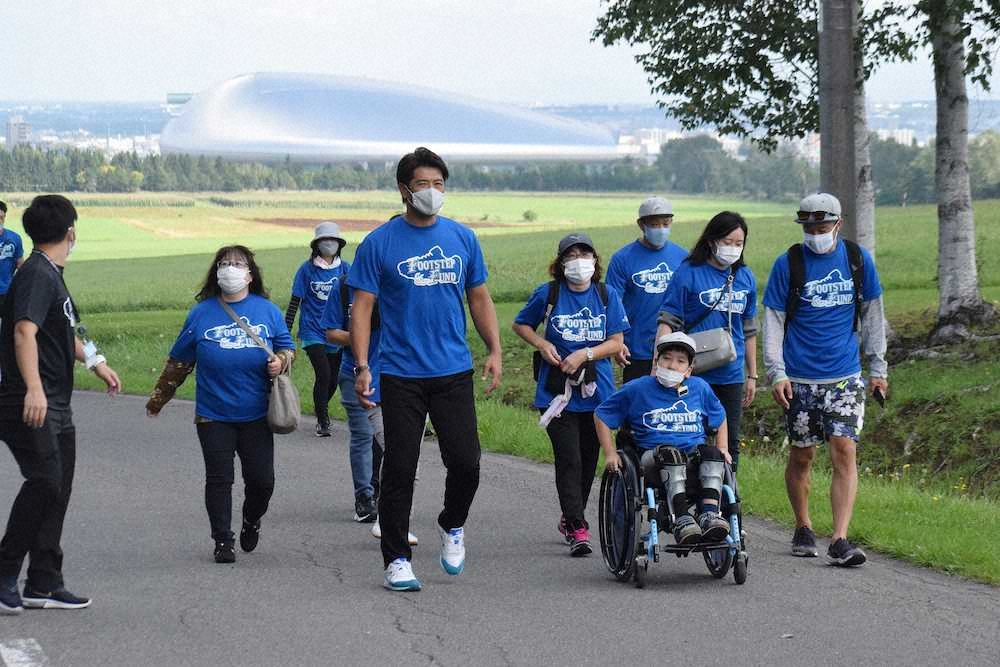 「FOOTSTEP　FUND～あしあと基金～」の活動で札幌ドームをバックに参加者とともにウォーキングする日本ハム・稲葉SCO（中央）