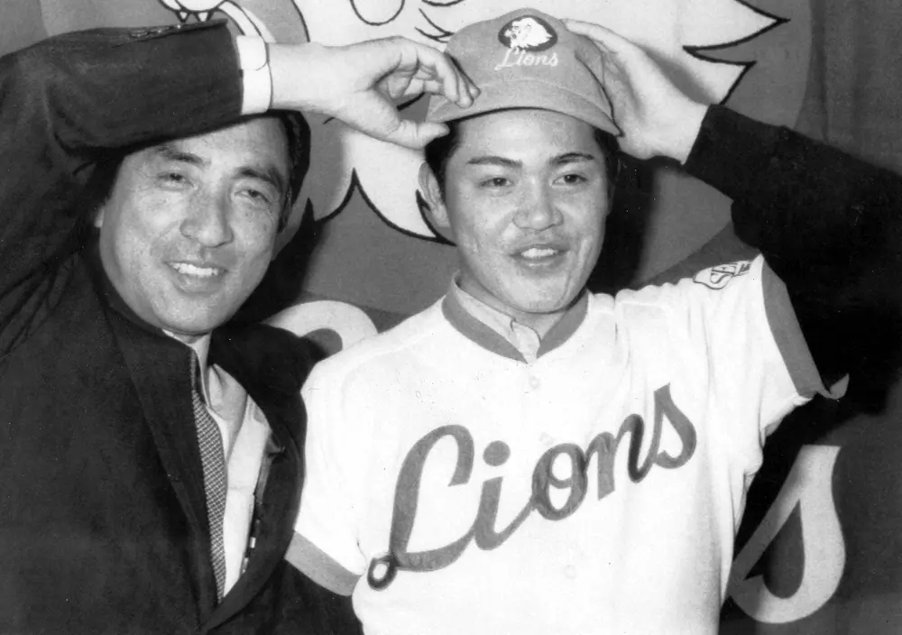 1982年1月、西武入団会見で坂井保之球団代表（左）に帽子をかぶせてもらう工藤公康投手