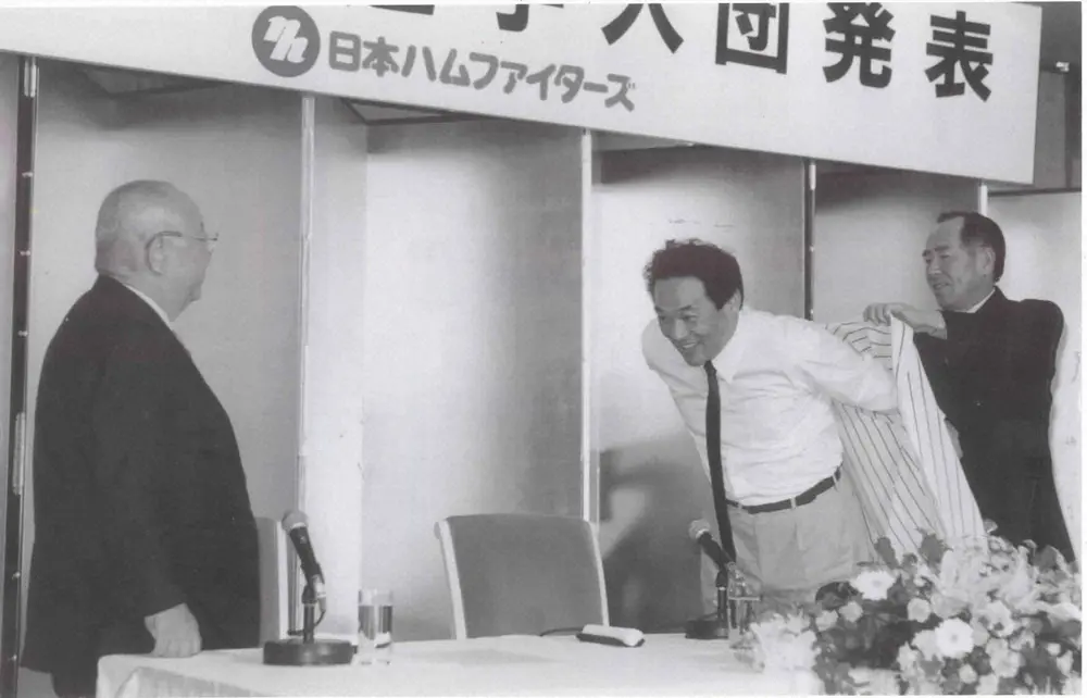 日本ハム入団会見で、大社義規オーナー（左）の見守る中、上田利治監督（右）に着せてもらう落合氏