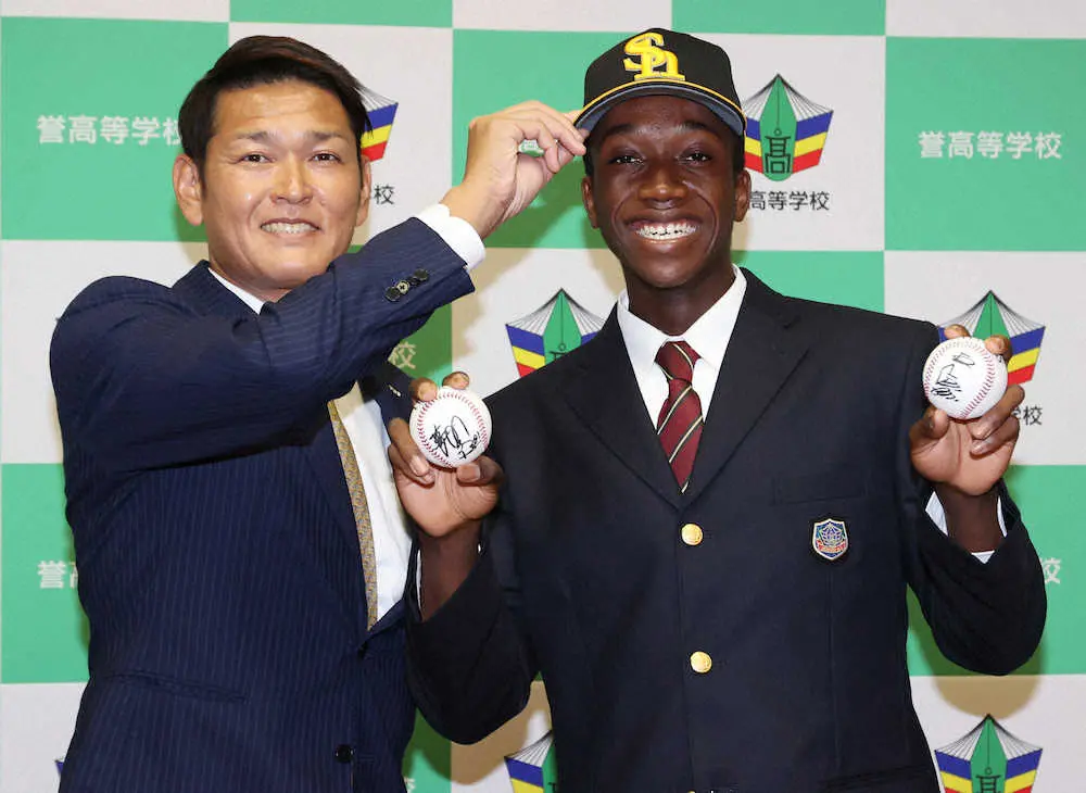 指名挨拶を終え、永井スカウト部長（左）から渡された藤本監督と王会長のサイン入りボールを手に笑顔のイヒネ（撮影・椎名　航）