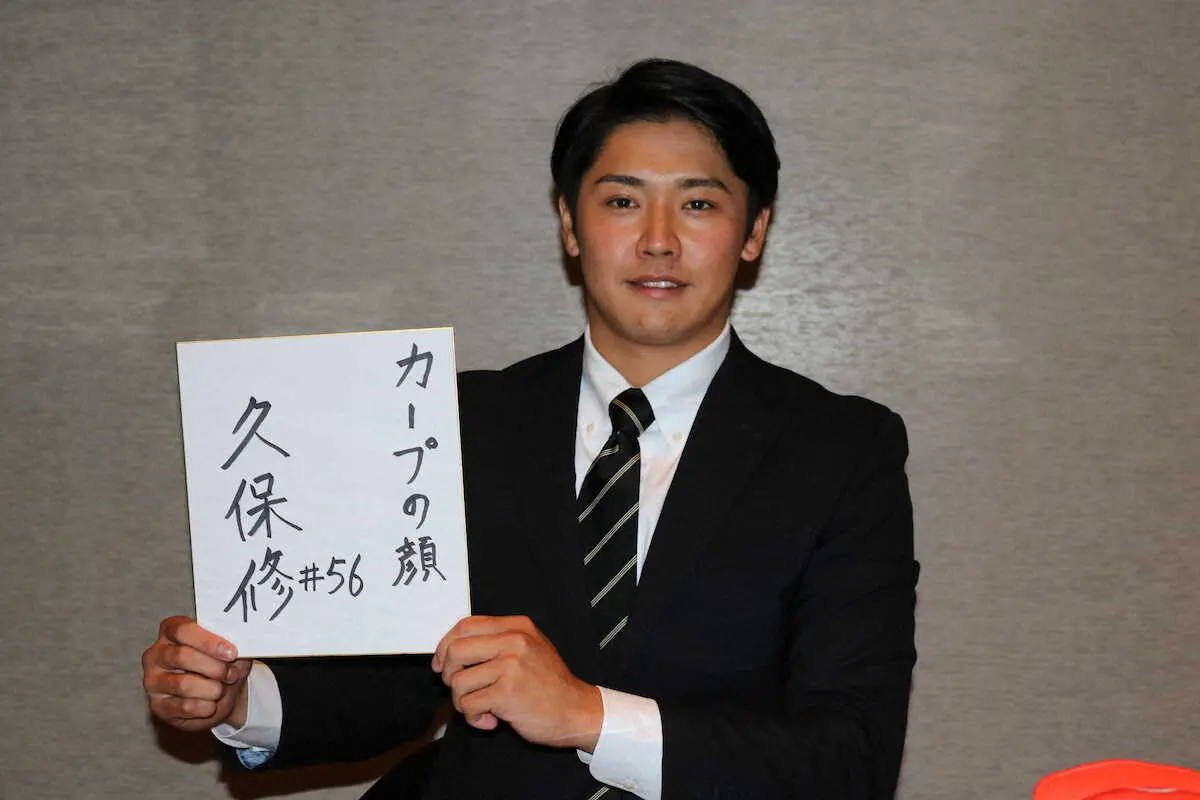 「カープの顔」と書いた色紙を手にする大阪観光大・久保