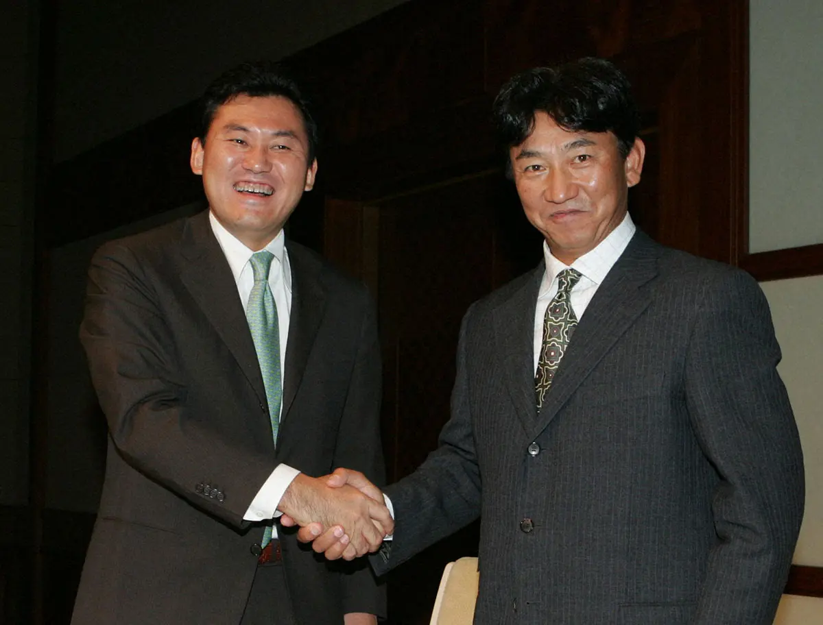 2004年10月、楽天の監督に就任し、会見で三木谷浩史社長（左）と笑顔で握手を交わす田尾安志氏