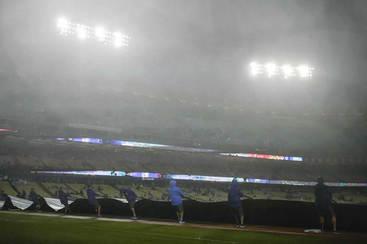 ドジャースタジアムでは9年ぶりの雨天中断となり、シートを敷く球場スタッフ（AP）