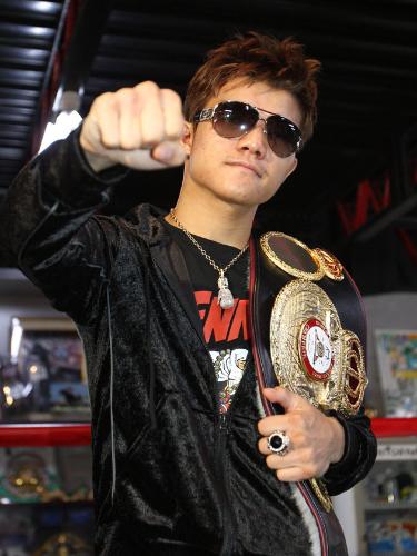 チャンピオンベルトを肩に掛け、拳を突き出す亀田大毅