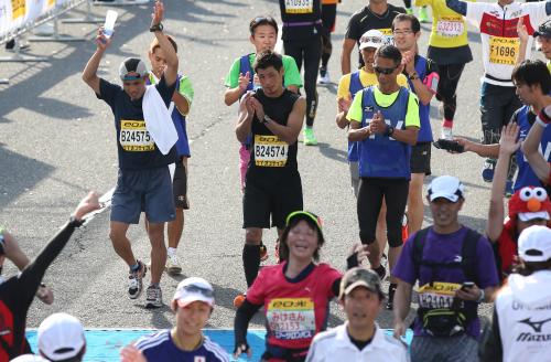 初マラソン挑戦で見事完走した長谷川穂積（中央）は拍手してゴール