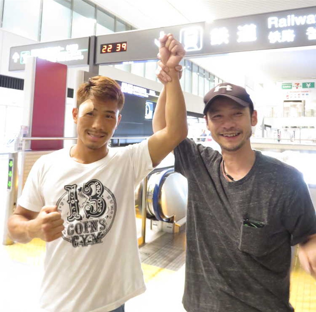 成田空港で有吉会長（右）に拳を上げられる新王者の木村