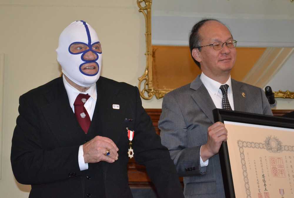 米ニューヨーク州バファローで行われた叙勲伝達式で、在ニューヨーク総領事館の高橋礼一郎総領事（右）から賞状を贈られた覆面姿のデストロイヤーさん