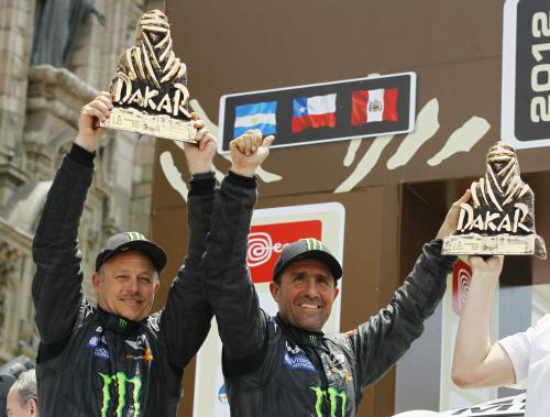 自動車のダカール・ラリーで優勝し、トロフィーを掲げるペテランセル（右）