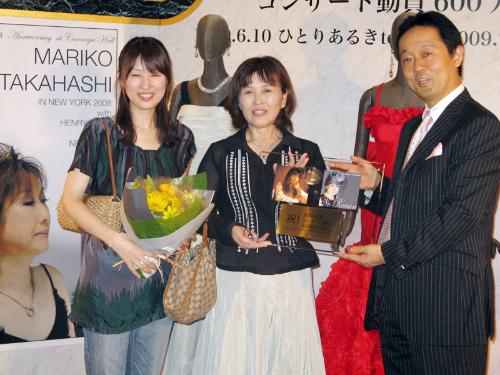 高橋真梨子コンサートの６００万人目の観客となった砂川弘子さん（中央）は所属レコード会社の加藤裕一社長から記念プレートを贈呈される。左は娘の真弓さん