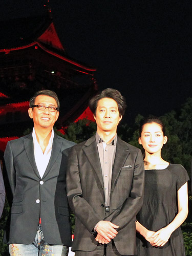 赤くライトアップされた大阪城の前に立つ（左から）中井貴一、堤真一、綾瀬はるか