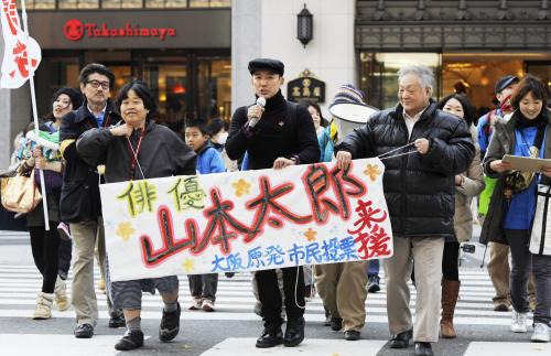 街頭を歩きながら、原発稼働の是非を問う住民投票の実施を求める署名を呼び掛ける山本太郎（中央）