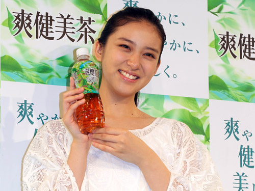 爽健美茶イメージキャラクターの武井咲は、商品を手に笑顔を見せる