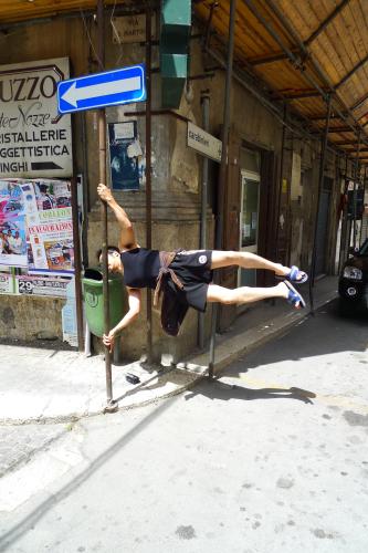 イタリア・シチリアのコルレオーネ村で一方通行の標識に対して垂直になる姿勢で腕力をアピールする天平