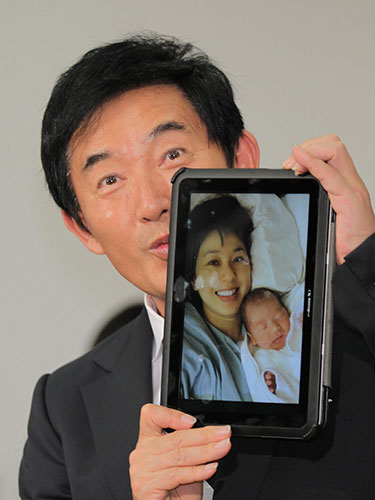 理子夫人と誕生した息子の写ったタブレット端末にキスをする石田純一