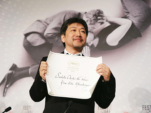 第６６回カンヌ国際映画祭授賞式後の記者会見で賞状を広げて見せる是枝監督