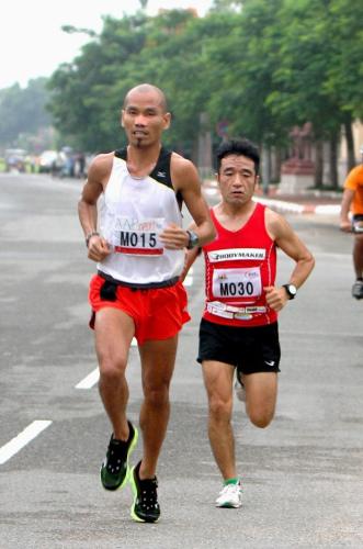 プノンペン国際ハーフマラソンで走るカンボジアのヘム・ブンティン（左）と猫ひろし