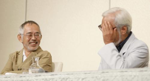 報道陣の質問に顔を一瞬隠す宮崎駿監督（右）を笑顔で見つめる鈴木敏夫プロデューサー