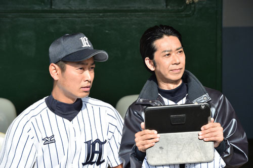 試合前、ベンチで日本生命野球部のデータを見る大道監督（手塚とおる・右）とキャプテンの井坂（須田邦裕・左）（Ｃ）ＴＢＳ