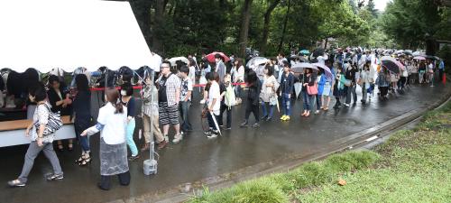 雨の降る中、傍聴券を求めて並ぶ大勢の人たち