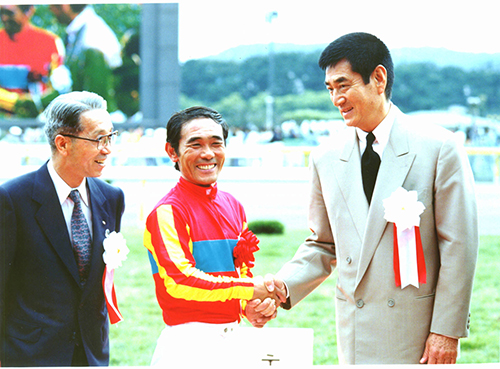 １９９３年のダービーを制した柴田政人騎手（左）と握手する高倉健さん（右）