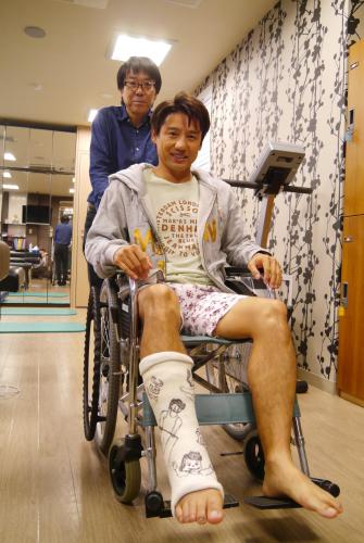 右アキレス腱断裂でギプス姿の池谷幸雄。体操界の大先輩、小西裕之さんに車椅子を押してもらう