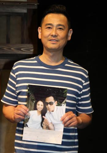 結婚報告会見で省子夫人との２ショット写真を持ち、写真撮影に応える野村宏伸