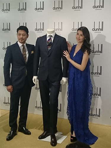 日本代表の公式スーツを挟んでポーズを取る橋本マナミと鈴木啓太