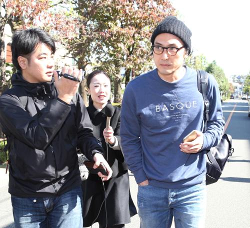 平幹二朗さんの自宅を訪れた長男の平岳大（右）は報道陣に囲まれながら帰路につく
