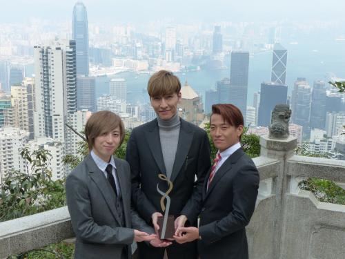 香港のヴィクトリア・ピークで絶景をバックに現地音楽賞のトロフィーを手にするｗ―ｉｎｄｓ．の（左から）千葉涼平、橘慶太、緒方龍一