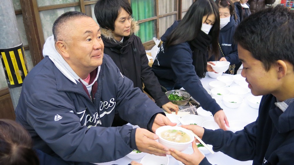 「トン汁炊き出し隊」の一員として商店街の客に熱い豚汁を振る舞う松村邦洋（左）、「ガガガＳＰ」の山本聡（左から２人目）