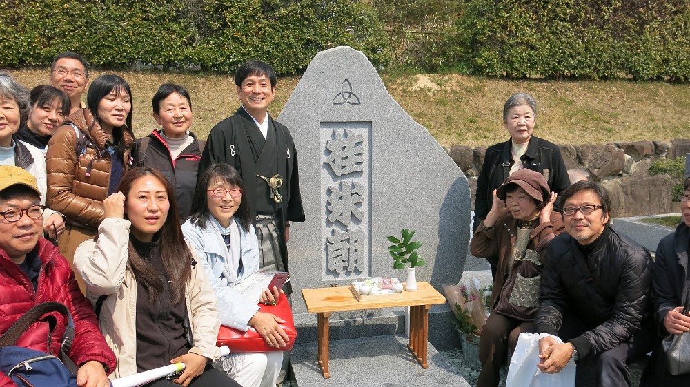 桂米朝さんの墓の前でファンと写真撮影する桂米團治（後列、墓の左）