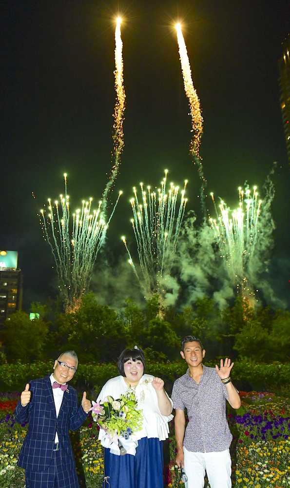 ＪＲ大阪駅北側の「うめきたガーデン」で花火をバックにポーズをとる酒井藍（中央）。左は石原和幸氏、右は「笑い飯」哲夫