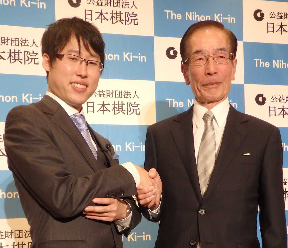 正式に国民栄誉賞受賞が決まり、大阪市内での会見で握手を交わす井山裕太七冠（左）と師匠の石井邦生九段