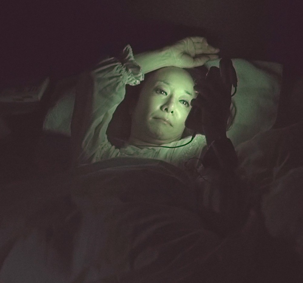 睡眠前にスマホを操作し、光を浴びる南美希子（Ｃ）ＴＢＳ