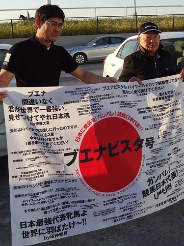 ブエナビスタへの応援コメントが寄せられた横断幕を掲げる松田博師（右）と山口厩務員