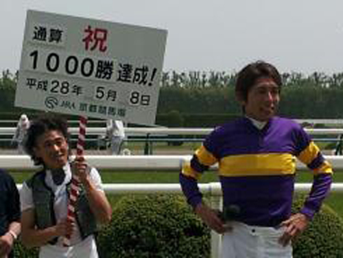 和田（右）がＪＲＡ通算１０００勝を達成し、同期の古川がプラカードを持って祝福する