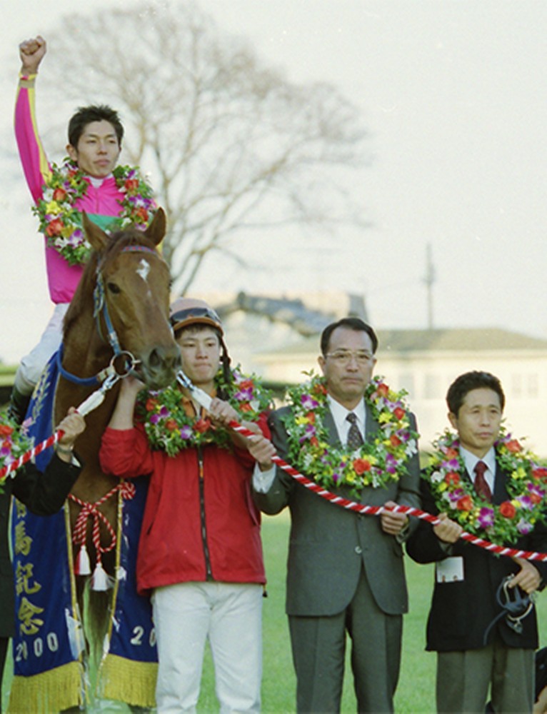 ００年、有馬記念を制し、テイエムオペラオーの鞍上でガッツポーズの和田。右端が岩元師