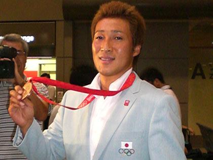 成田空港に到着し、銅メダルを掲げる永井