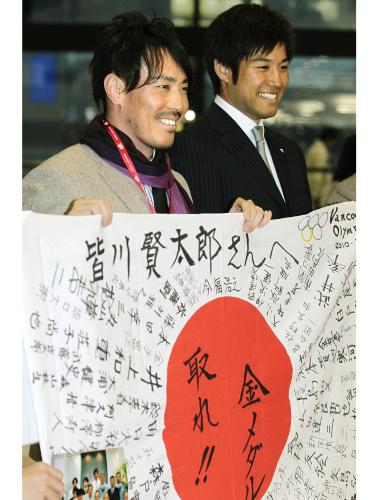 寄せ書きされた日の丸を手に笑顔を見せるアルペンスキーの皆川賢太郎（左）