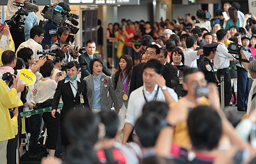 帰国する日本選手団を出迎えるファンと報道陣でごった返す空港内。中央はレスリング女子５５キロ級金メダルの吉田