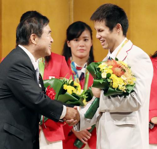 リオデジャネイロ五輪・パラリンピック水泳日本代表の報告会で、遠藤前五輪相（左）から花束を受け取る木村敬一