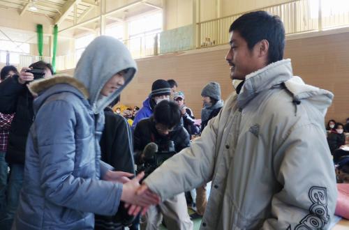 避難所で被災者と握手を交わす鹿島アントラーズの小笠原満男選手（右）