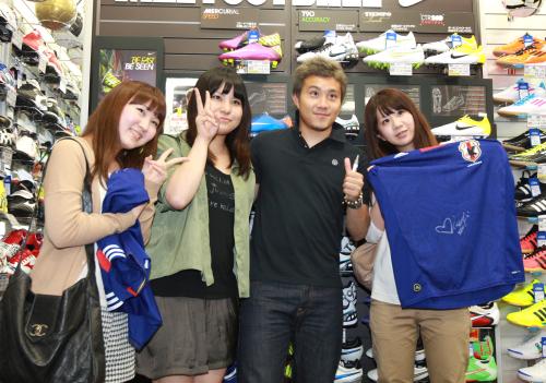 １日店長を務めたサッカー日本代表・安田はファンにサインし笑顔を見せる