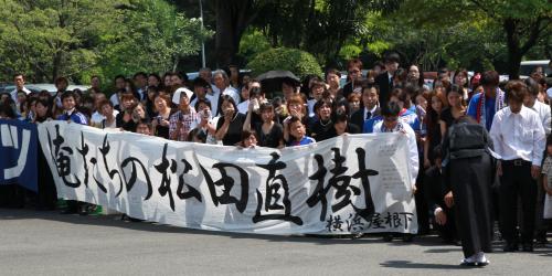 松田さんの横断幕を掲げたサポーターに一礼する母・正恵さん（右手前）