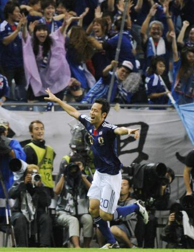 ＜日本・北朝鮮＞試合終了間際に決勝ゴールを決め、両手を広げ駆けだす吉田と大喜びの日本サポーター