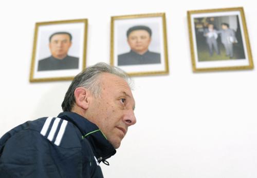 記者会見を終え、会場を引き揚げるサッカー日本代表のザッケローニ監督。上は北朝鮮の金正日総書記親子の肖像画