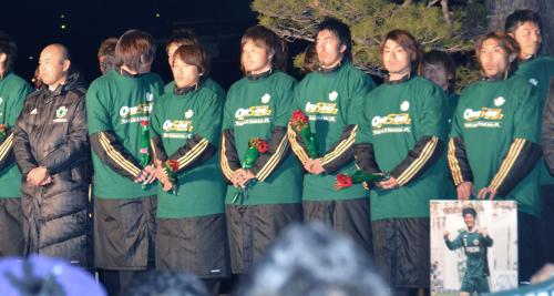 故松田直樹選手の写真を手にサポーターにＪ２昇格を報告する木島（右端）ら松本山雅イレブン