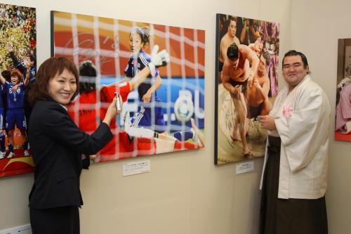 報道写真展の来場の記念として、自身が写ったパネルに笑顔でサインをする「なでしこジャパン」の丸山桂里奈（左）と琴奨菊