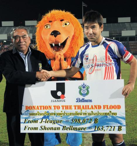 タイのサッカーリーグの会長（左）に、洪水被災者への義援金を渡す丸山良明さん